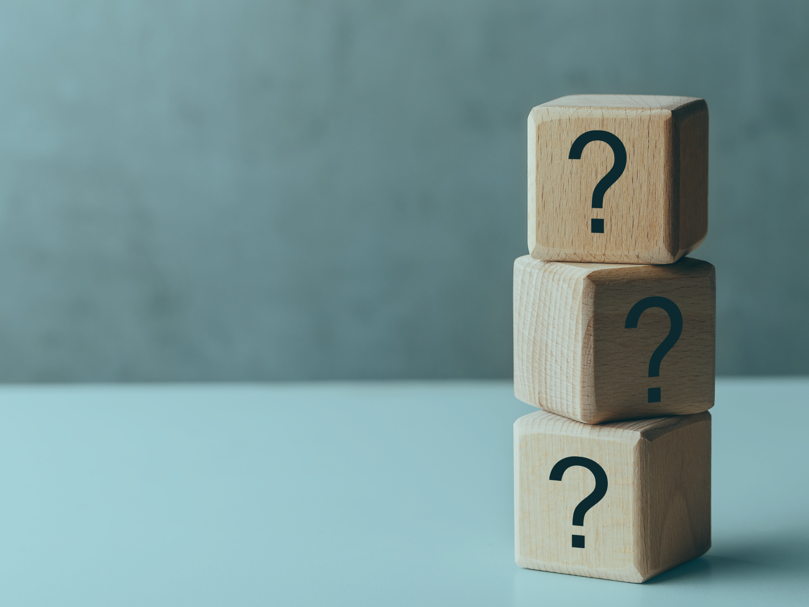 Cubos de madera apilados con signos de interrogación que simbolizan el pensamiento crítico y el poder de las preguntas en el aprendizaje