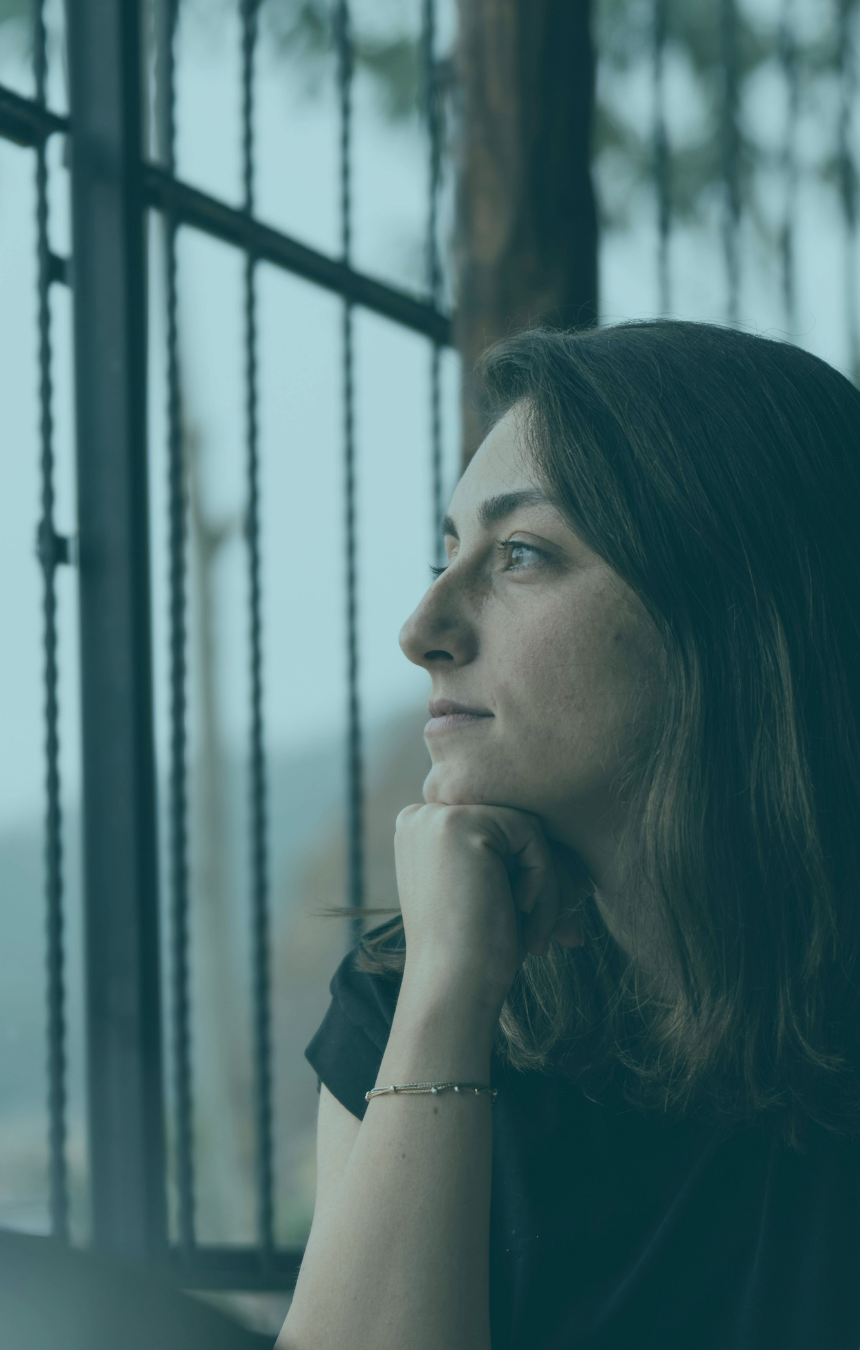 Mujer reflexionando junto a una ventana, en actitud de concentración.