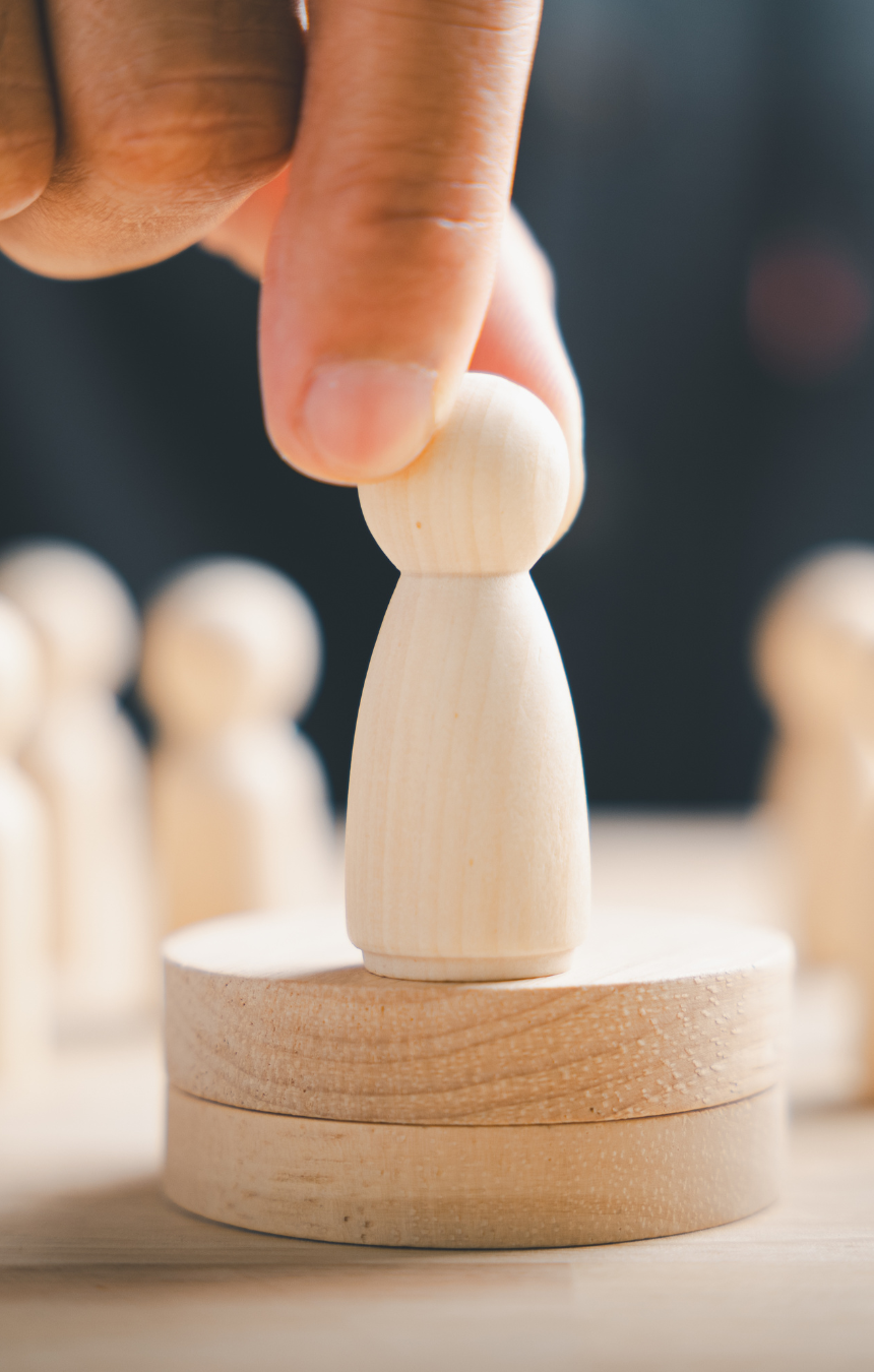 Mano colocando una figura de madera sobre una base, simbolizando la toma de decisiones y el papel del liderazgo en la organización