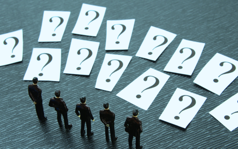 Figuras en miniatura observan múltiples tarjetas con signos de interrogación, simbolizando la reflexión, el pensamiento crítico y la búsqueda de respuestas a través de preguntas poderosas.