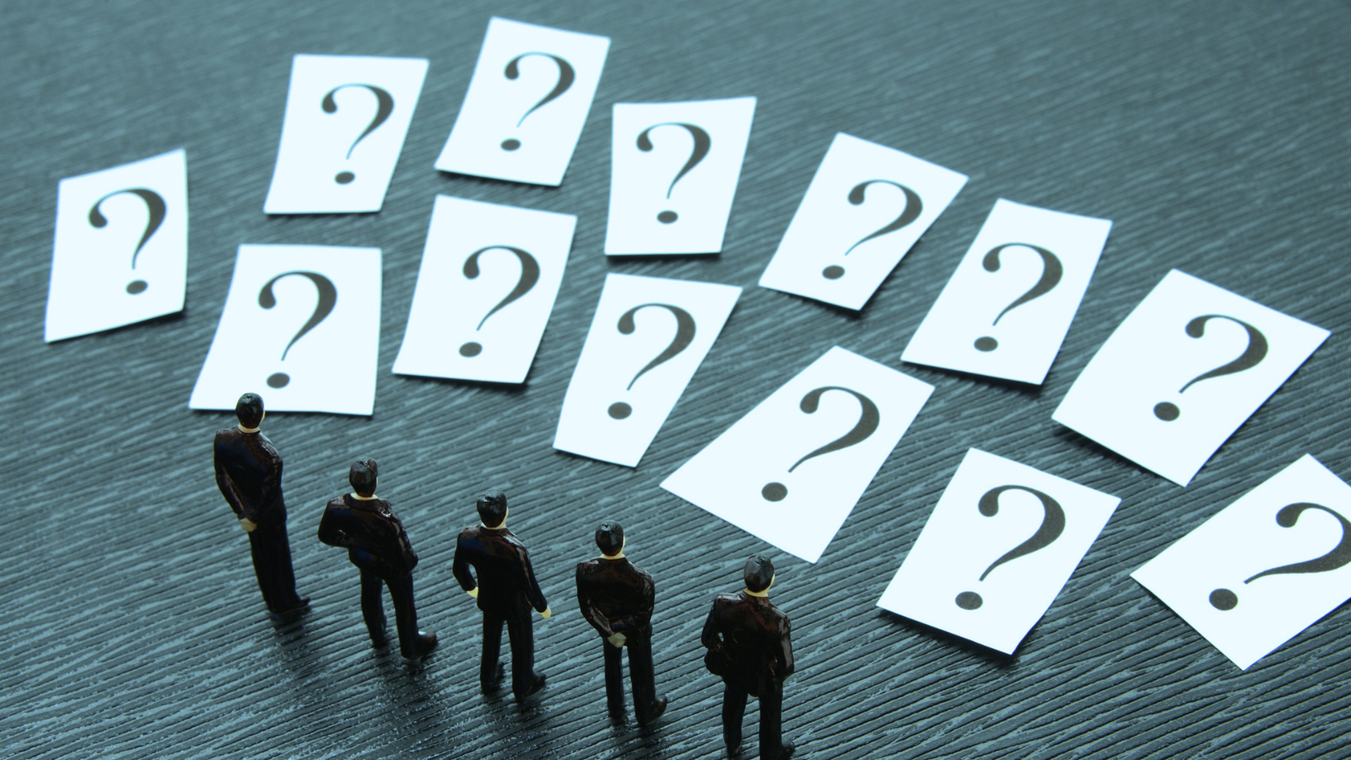 Figuras en miniatura observan múltiples tarjetas con signos de interrogación, simbolizando la reflexión, el pensamiento crítico y la búsqueda de respuestas a través de preguntas poderosas.
