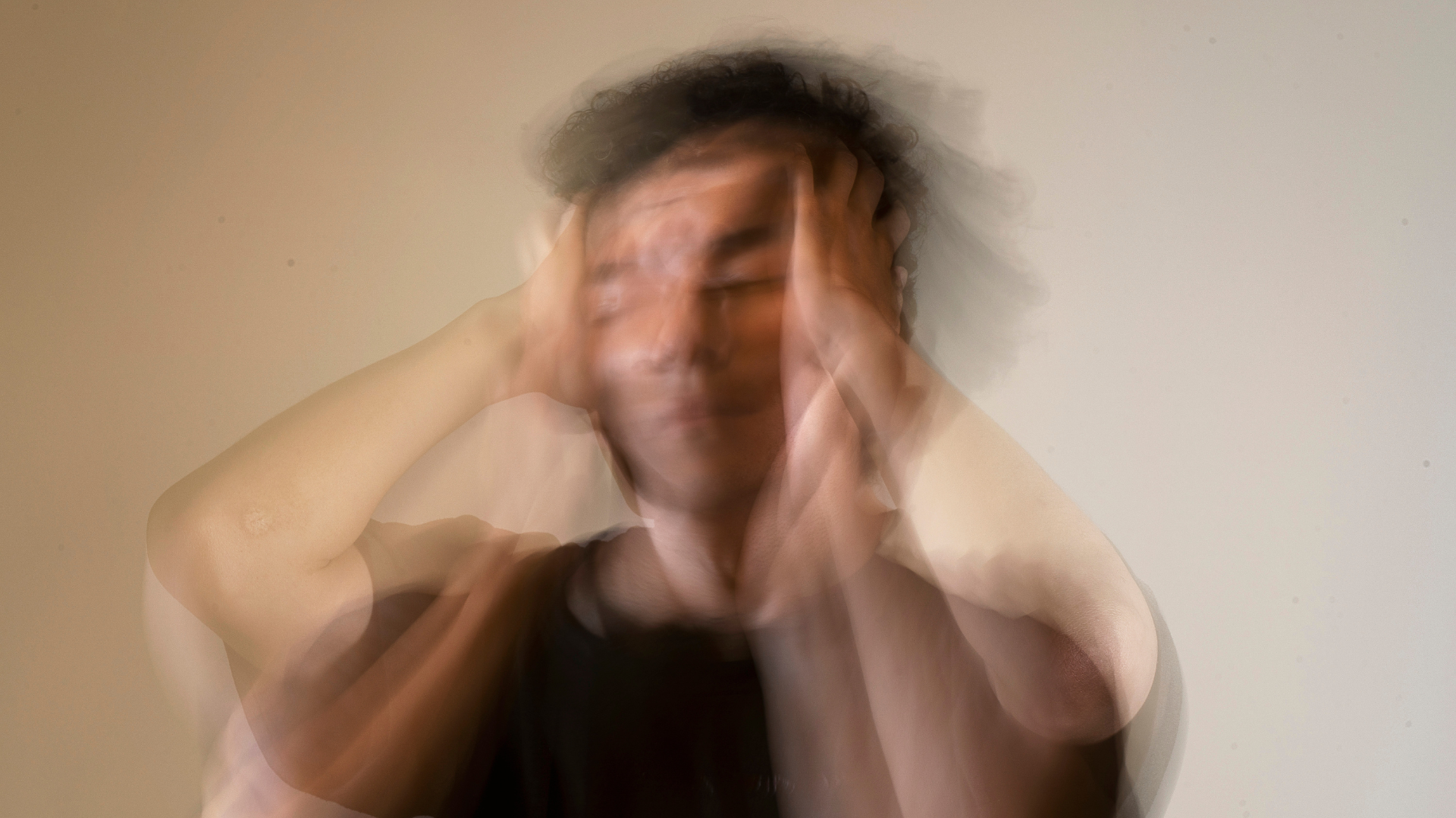 Hombre desenfocado llevándose las manos a la cabeza, representando estrés o agotamiento emocional