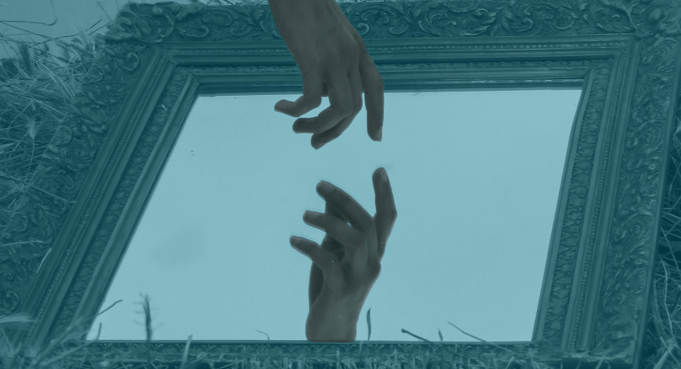 Manos que se acercan y se reflejan en un espejo de marco ornamentado sobre la hierba, una metáfora del autoconocimiento y la percepción personal.